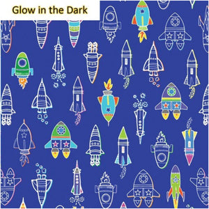 A piece of fabric featuring a pattern of colorful rockets and stars on a blue background, labeled 'Glow in the Dark'.