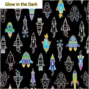 A piece of fabric featuring a pattern of colorful rockets and space-themed designs on a black background, labeled 'Glow in the Dark'.