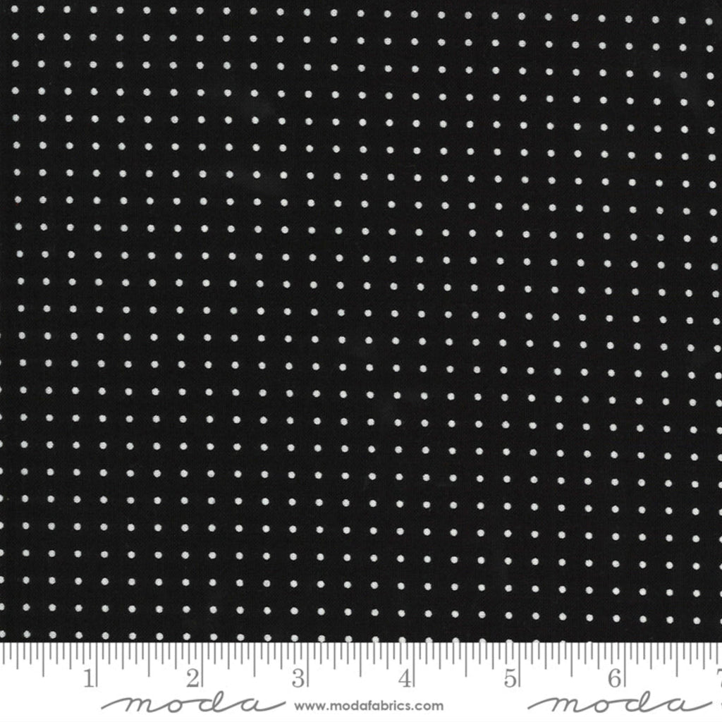 Black fabric with white polka dots and a ruler at the bottom for scale.
