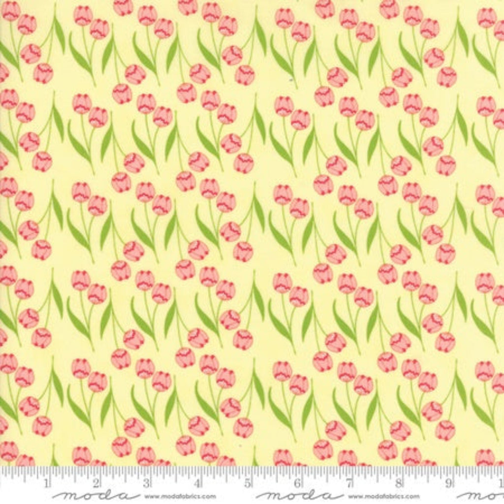 A piece of fabric with a floral pattern consisting of small pink flowers and green leaves on a yellow background, with a ruler at the bottom showing the measurement scale.
