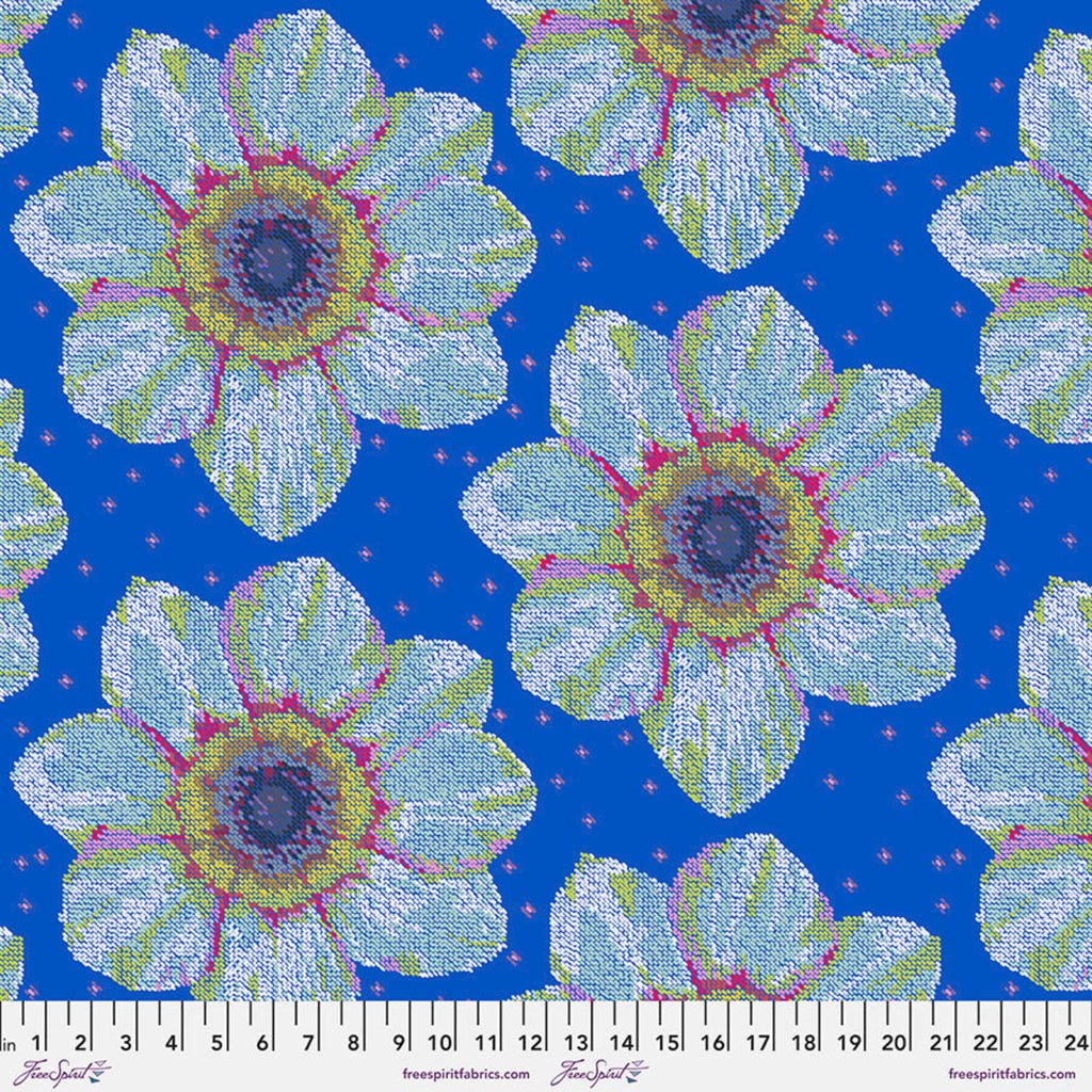 A piece of fabric featuring a large floral pattern with blue, white, green, and pink colors on a ruler for scale.