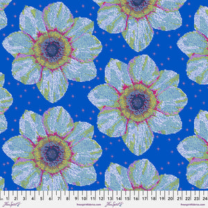 A piece of fabric featuring a large floral pattern with blue, white, green, and pink colors on a ruler for scale.