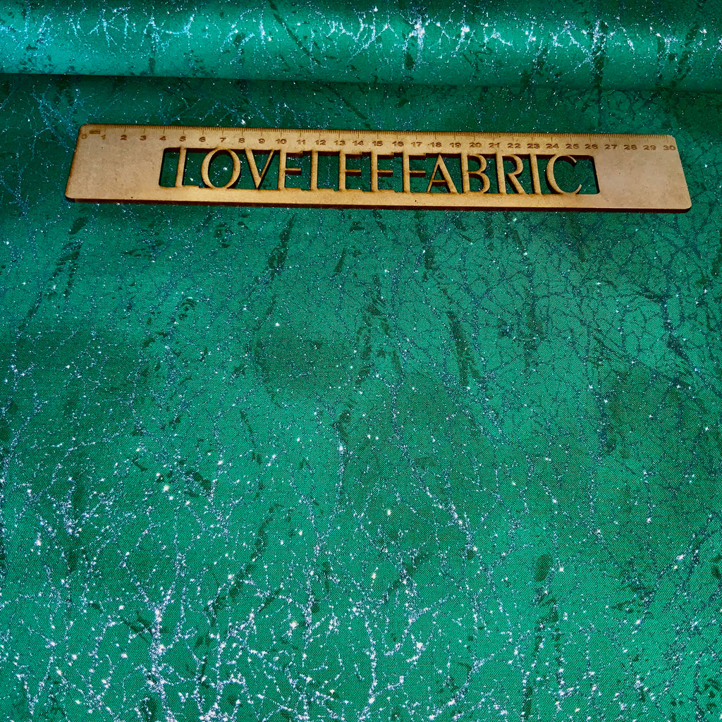 A piece of green fabric with a metallic texture featuring a diamond dust design, with the brand 'Love the Fabric' imprinted on it.