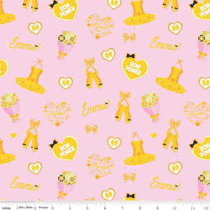 A pink fabric with yellow accents, featuring patterns including ballet shoes, hearts, and the name 'Emma'.