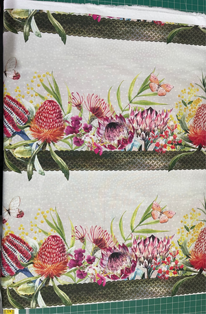 Floral patterned fabric with a green border on a cutting mat.
