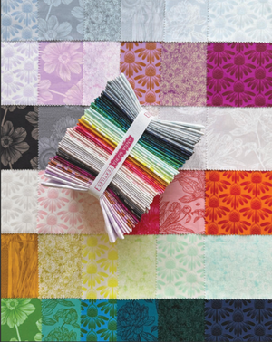 Color swatch book with fabric samples on a patchwork quilt background