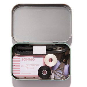 Open tin containing sewing supplies with 'SOHMO' branding on a white background