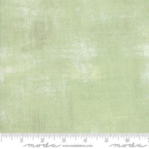 Textured light green fabric with a ruler at the bottom for scale