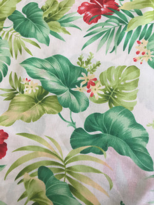 A piece of Lecien fabric featuring a tropical print with leaves and flowers in green, red, and other colors on a white background.
