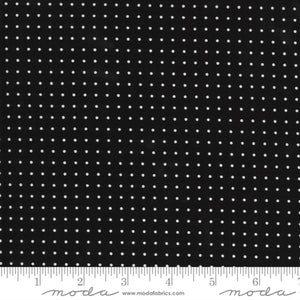 Black fabric with white polka dots and a ruler at the bottom for scale.